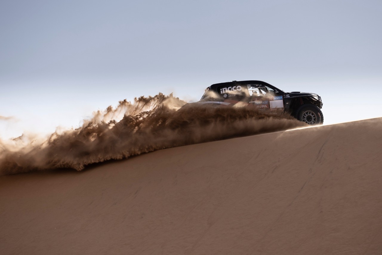 Toyota Hilux jede pouští, za koly vozu odlétá písek
